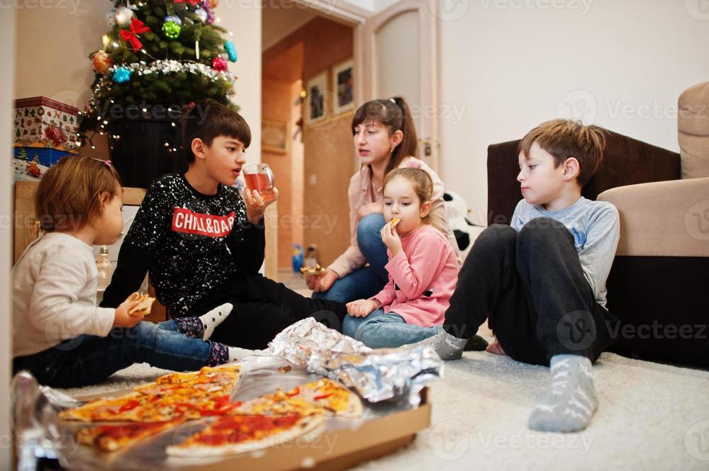 happy-family-with-four-kids-eating-pizza-at-home-photo